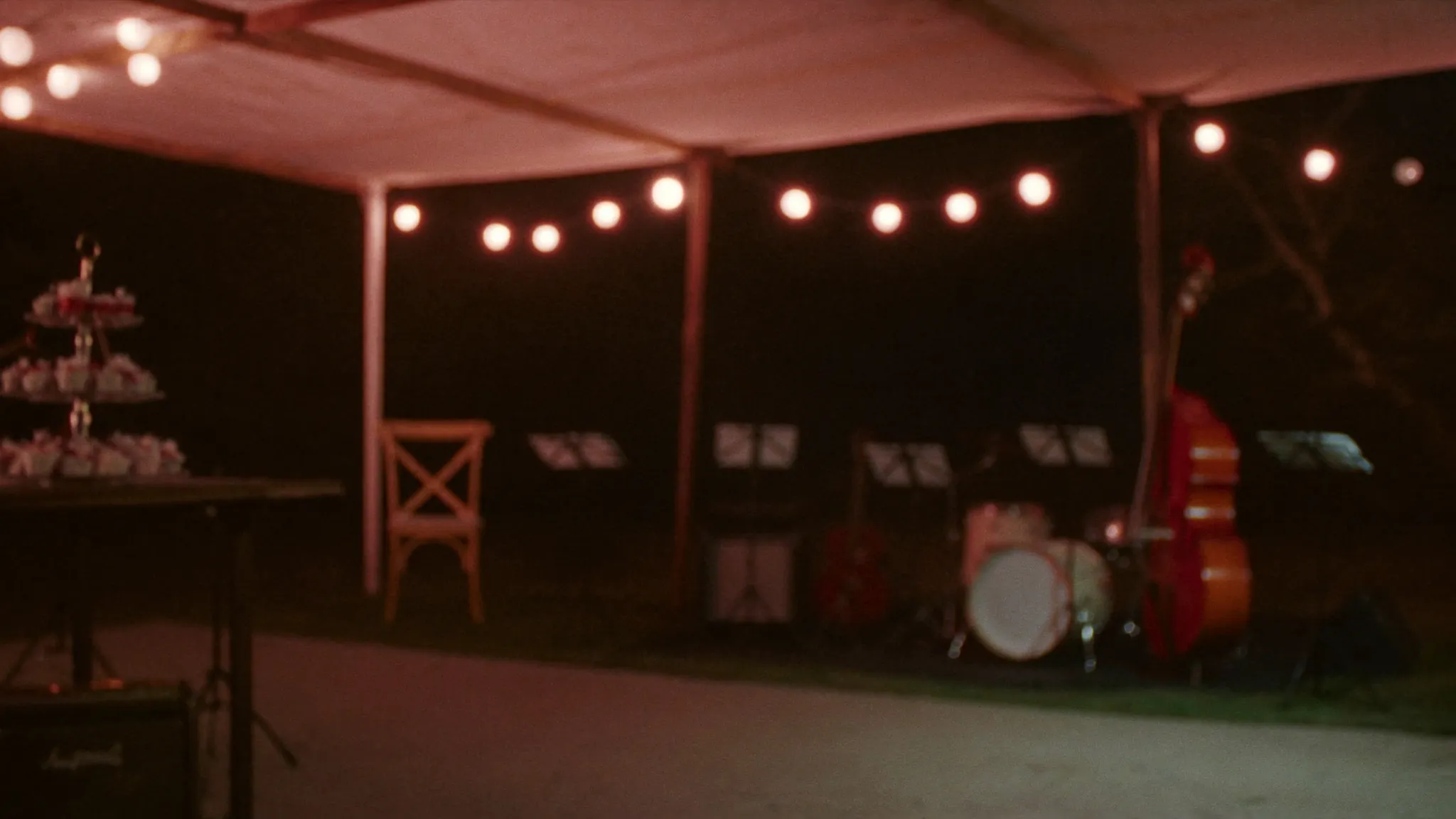 An evening wedding reception with warm bistro string lights and a band setup